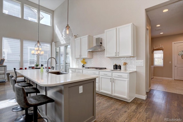 kitchen with backsplash, a breakfast bar area, plenty of natural light, wall chimney exhaust hood, and a sink