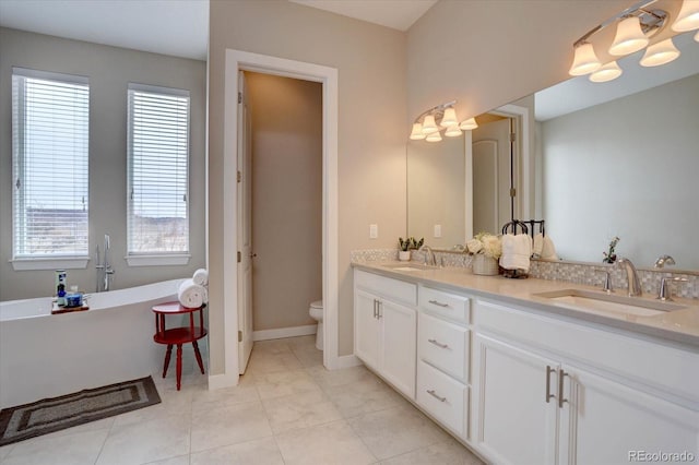 full bathroom featuring a sink, a freestanding tub, toilet, and double vanity