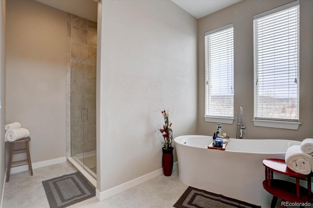 full bathroom featuring a shower stall, a freestanding tub, baseboards, and tile patterned floors