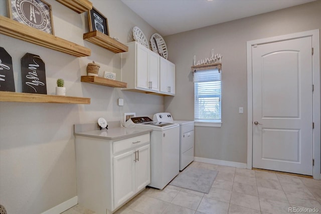 washroom featuring cabinet space, light tile patterned floors, separate washer and dryer, and baseboards