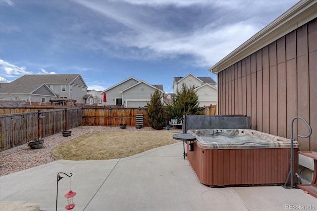 view of patio featuring a residential view, a hot tub, and a fenced backyard