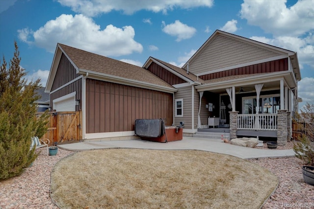 rear view of property featuring fence, board and batten siding, covered porch, a shingled roof, and a garage