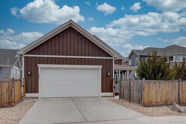 view of front facade featuring board and batten siding, concrete driveway, an attached garage, and fence