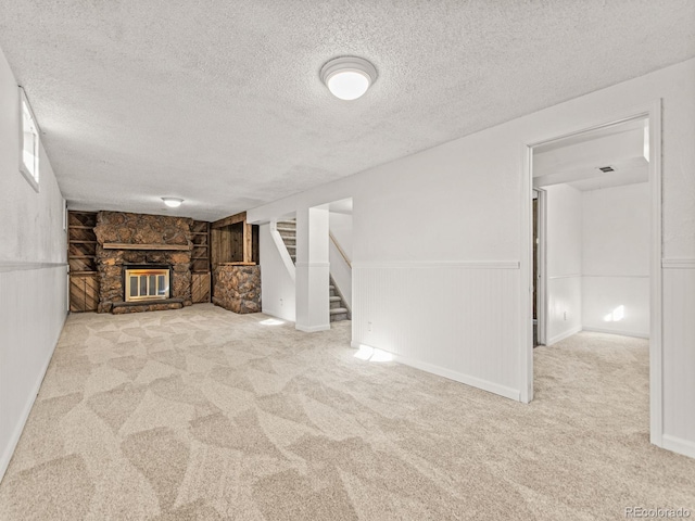 unfurnished living room with a stone fireplace, light carpet, and a textured ceiling