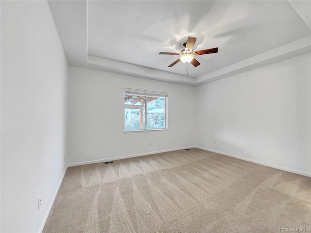 carpeted empty room featuring ceiling fan and a tray ceiling