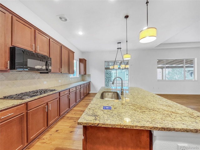 kitchen with sink, backsplash, a center island with sink, and stainless steel gas stovetop