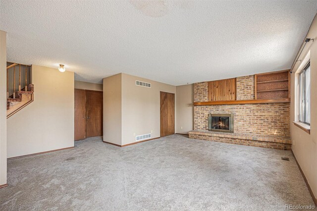17583 E Belleview Pl, Centennial, CO 80015 - unfurnished living room featuring stairs, carpet floors, a fireplace, and a textured ceiling