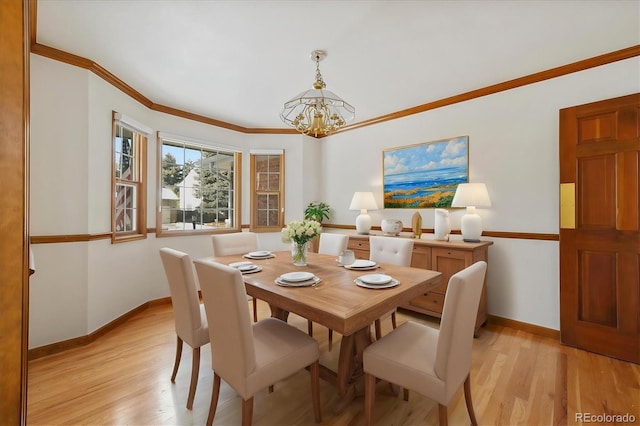 dining space with light hardwood / wood-style flooring, crown molding, and a chandelier