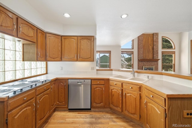 kitchen featuring appliances with stainless steel finishes, light hardwood / wood-style flooring, kitchen peninsula, and sink