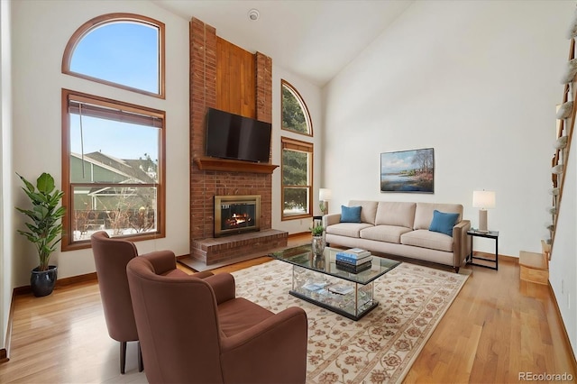 living room featuring light wood-type flooring, a fireplace, and high vaulted ceiling