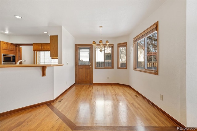 unfurnished dining area featuring an inviting chandelier and light hardwood / wood-style floors