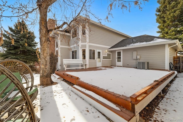 snow covered rear of property featuring central AC