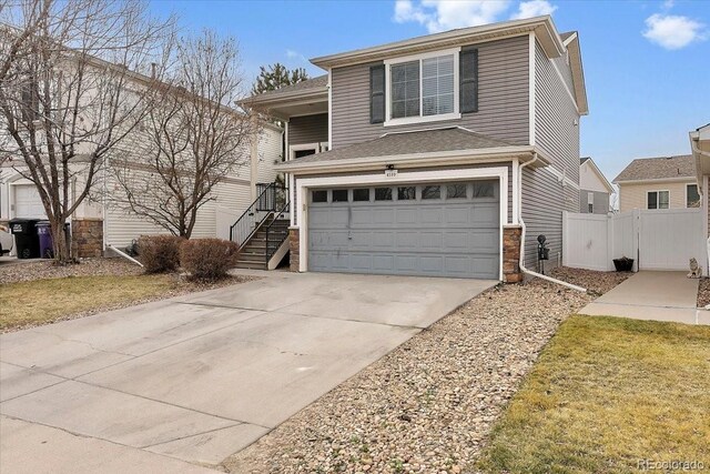 traditional home featuring a gate, fence, stairs, concrete driveway, and a garage