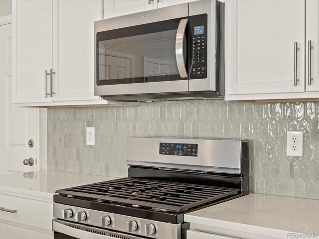20982 E 66th Ave, Aurora, CO 80019 - kitchen with decorative backsplash, light stone counters, white cabinetry, and appliances with stainless steel finishes