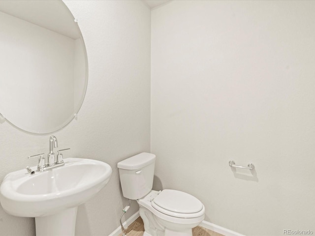20982 E 66th Ave, Aurora, CO 80019 - bathroom with wood finished floors, toilet, baseboards, and a sink