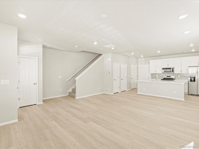 20982 E 66th Ave, Aurora, CO 80019 - unfurnished living room featuring light wood-style flooring, baseboards, recessed lighting, and stairs