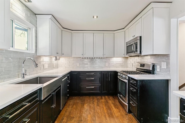 5480 W Iowa Ave, Lakewood, CO 80232 - kitchen with appliances with stainless steel finishes, white cabinets, light countertops, and dark cabinetry