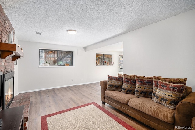 7746 W Quarto Dr, Littleton, CO 80128 - living room with a wealth of natural light, a brick fireplace, wood finished floors, and visible vents