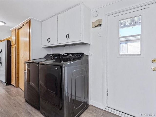 laundry room featuring light hardwood / wood-style flooring, washer and clothes dryer, and cabinets