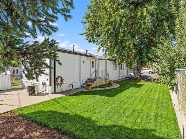 back of house with central AC and a lawn