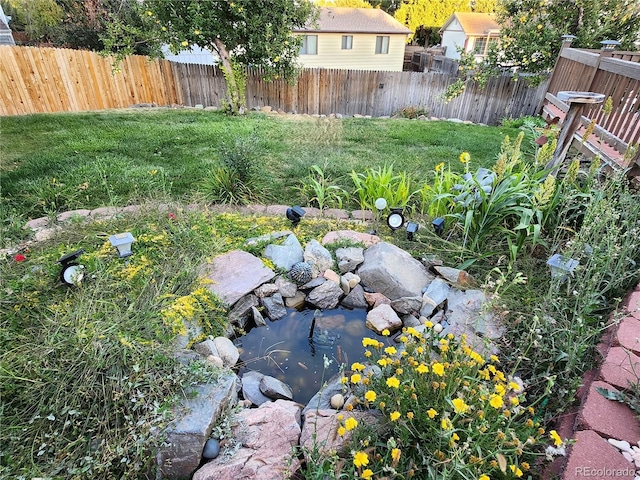 view of yard featuring fence and a garden pond