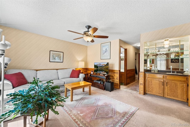 16085 E Lehigh Cir, Aurora, CO 80013 - living room featuring wallpapered walls, a wainscoted wall, ceiling fan, light colored carpet, and a textured ceiling
