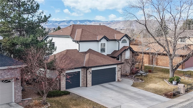 view of front of house with a garage, driveway, roof with shingles, a mountain view, and a front yard