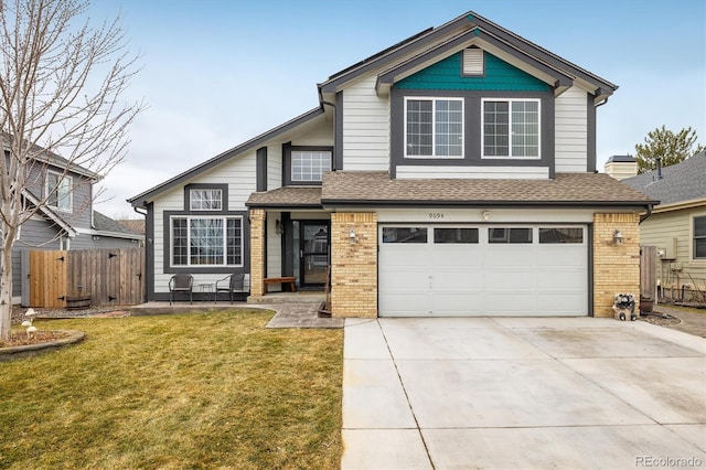 traditional-style house featuring a front yard, fence, driveway, a garage, and brick siding