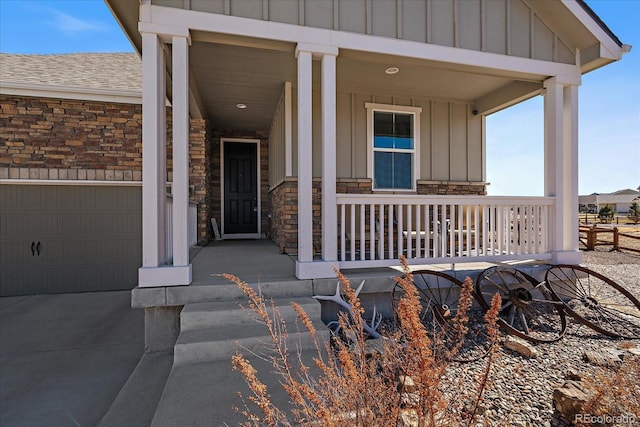 doorway to property featuring board and batten siding, stone siding, roof with shingles, and a porch