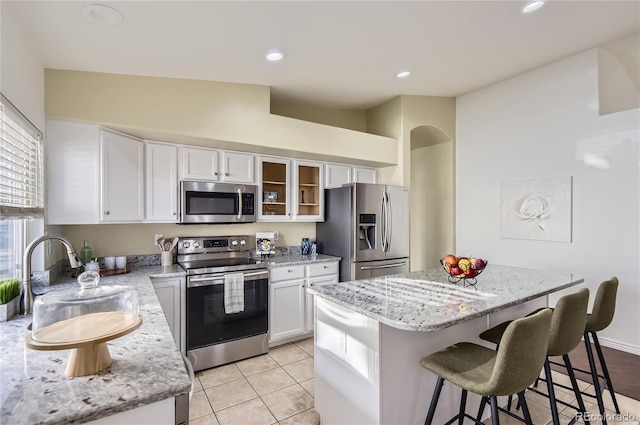 kitchen with a center island, white cabinets, sink, appliances with stainless steel finishes, and light tile patterned flooring