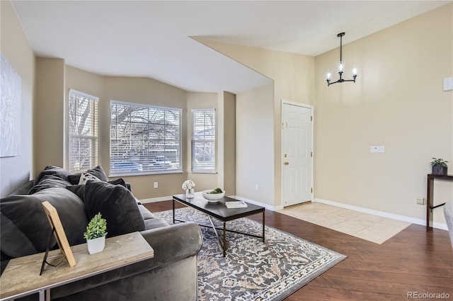 living room featuring vaulted ceiling, a healthy amount of sunlight, a notable chandelier, and wood-type flooring