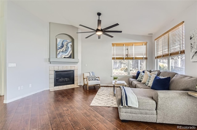 living room with dark hardwood / wood-style flooring, ceiling fan, lofted ceiling, and a tiled fireplace