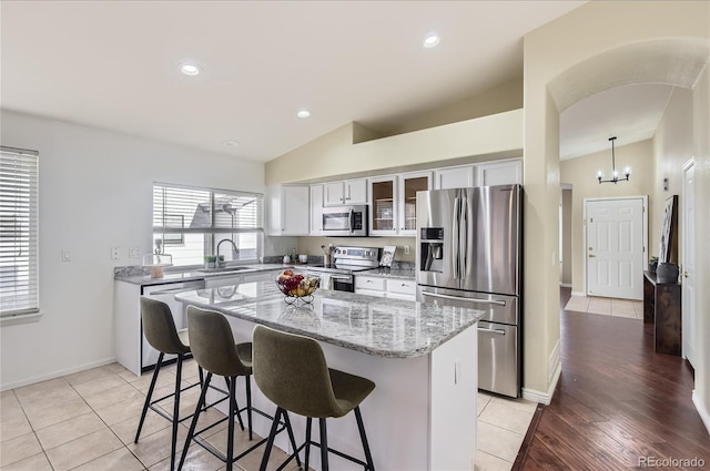 kitchen with sink, a center island, light tile patterned floors, and appliances with stainless steel finishes