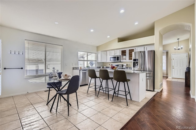 kitchen with a center island, stainless steel appliances, vaulted ceiling, and hanging light fixtures