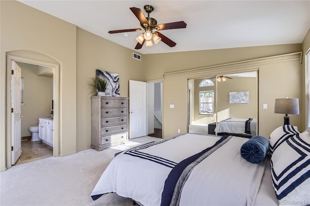 bedroom with ensuite bath, ceiling fan, light colored carpet, and lofted ceiling