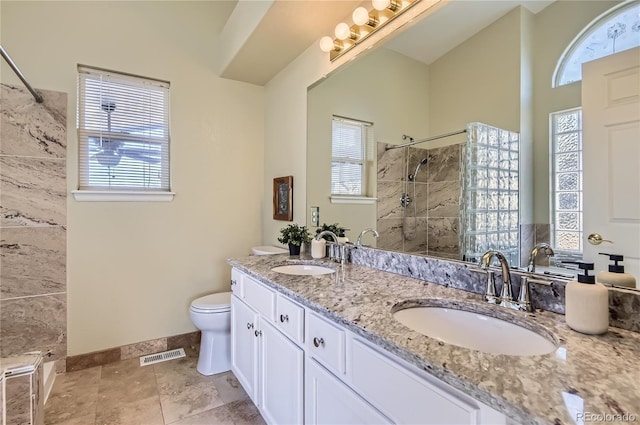 bathroom featuring a tile shower, vanity, and toilet