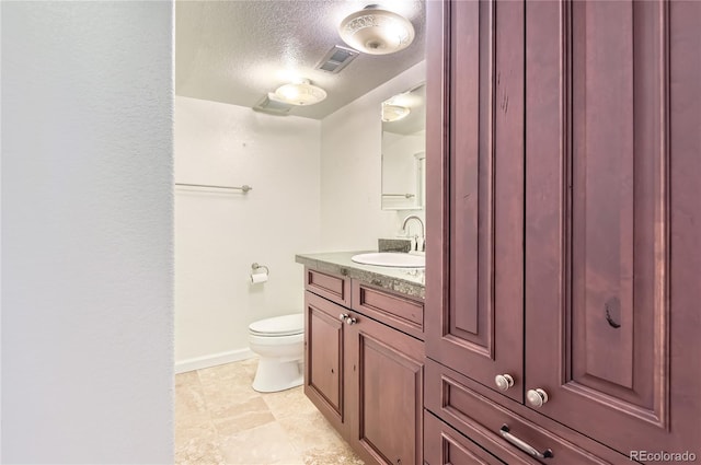 bathroom featuring vanity, a textured ceiling, and toilet