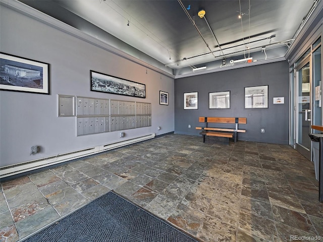 playroom featuring baseboard heating, mail area, baseboards, track lighting, and stone tile floors