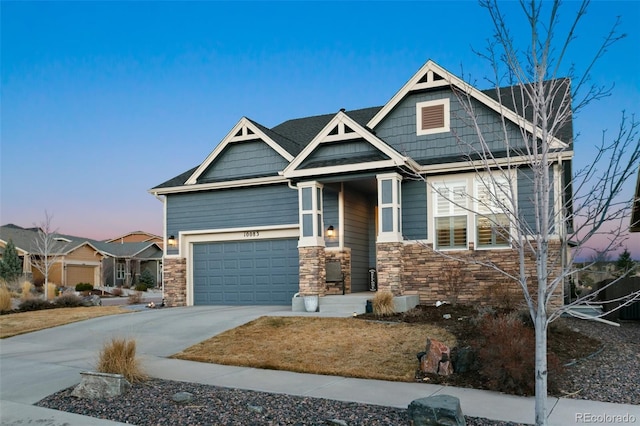 craftsman-style house with a garage, driveway, and stone siding