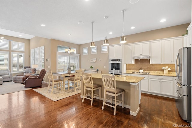 kitchen with open floor plan, appliances with stainless steel finishes, dark wood-style floors, and a wealth of natural light