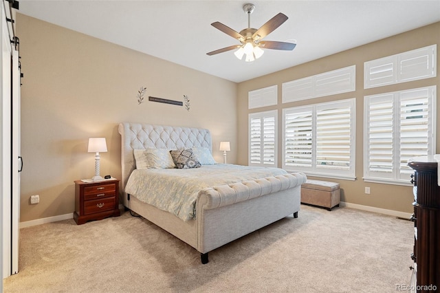 bedroom featuring baseboards, ceiling fan, a barn door, and light colored carpet