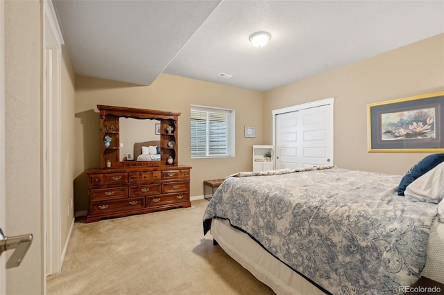 bedroom featuring a textured ceiling, light carpet, visible vents, baseboards, and a closet