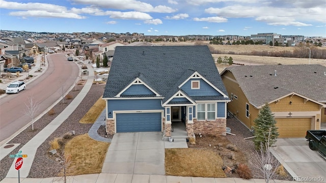 view of front of house featuring driveway, a shingled roof, stone siding, a residential view, and an attached garage