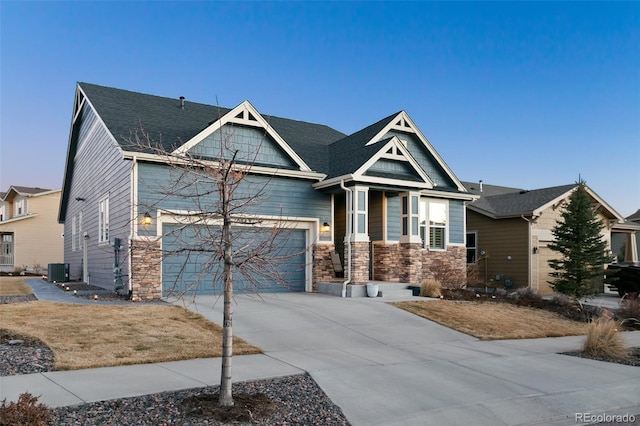 craftsman-style house with stone siding, concrete driveway, central AC, and a shingled roof