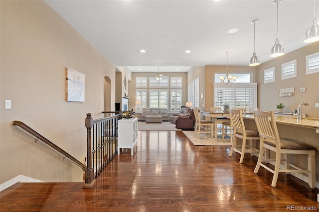 dining area with a notable chandelier, arched walkways, wood finished floors, and recessed lighting