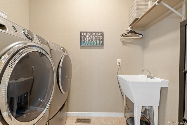 clothes washing area featuring laundry area, separate washer and dryer, a sink, visible vents, and baseboards