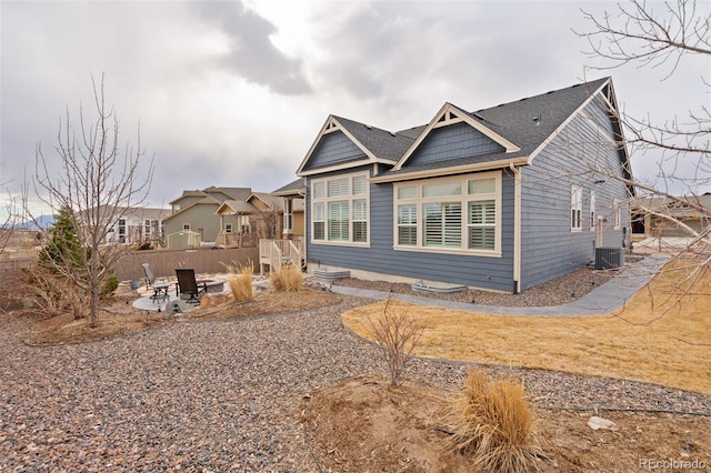 view of front of property with a patio area, fence, a fire pit, and cooling unit