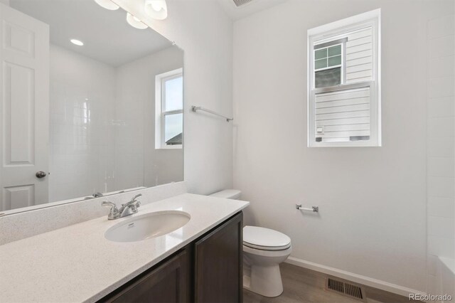 6625 N Nepal St, Aurora, CO 80019 - full bathroom with toilet, vanity, wood finished floors, baseboards, and visible vents