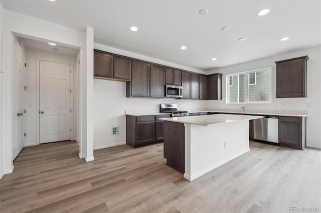 6625 N Nepal St, Aurora, CO 80019 - kitchen with a kitchen island, dark brown cabinetry, appliances with stainless steel finishes, and light wood-type flooring