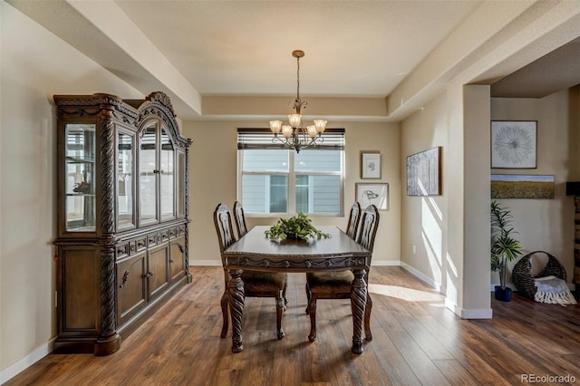 dining room featuring dark hardwood / wood-style floors, a tray ceiling, and a notable chandelier